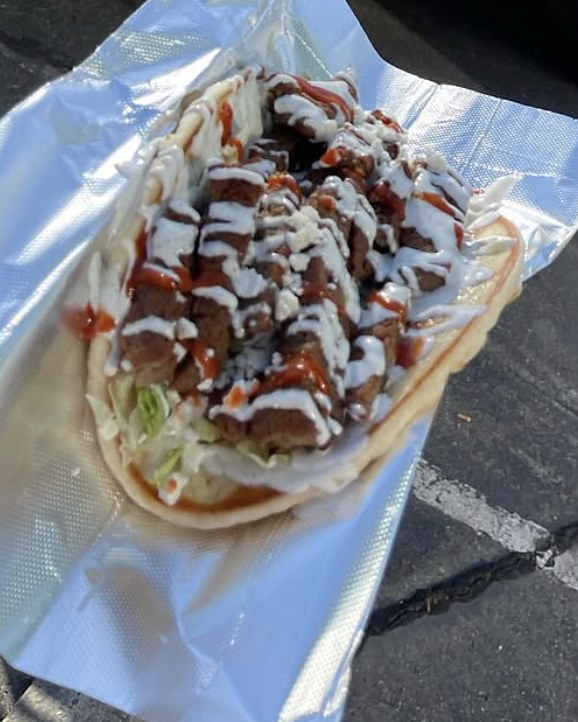 A gyro pita on foil with lamb, lettuce and tzatziki