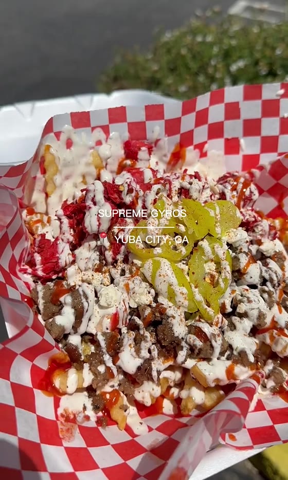 Sauce being poured over a tray of fries