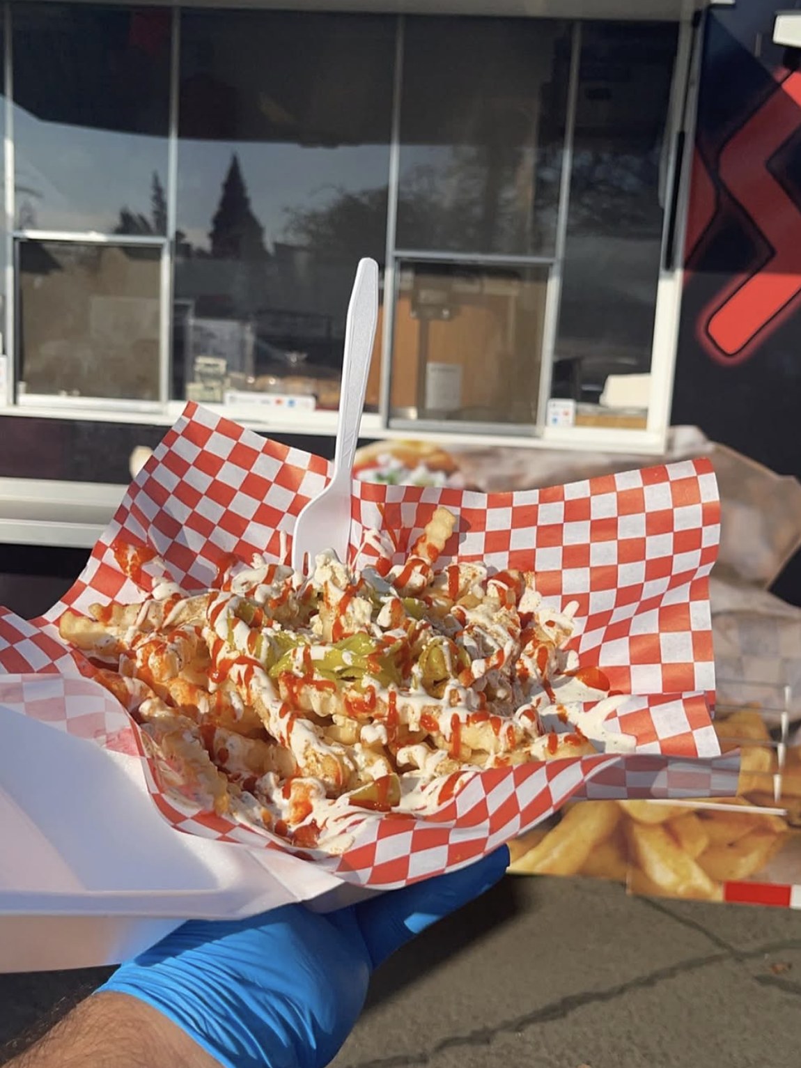 A tray of loaded fries handed over the counter in front of the truck
