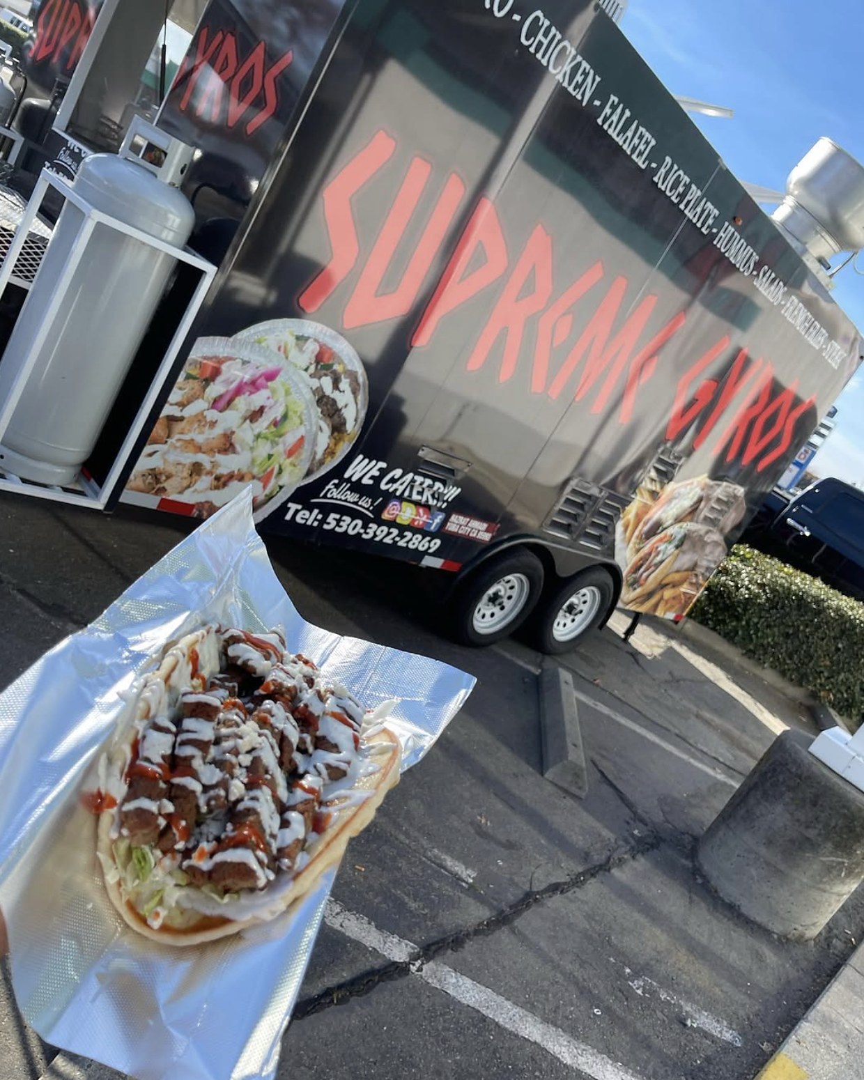 A gyro pita in front of the Supreme Gyros truck at a catering stop